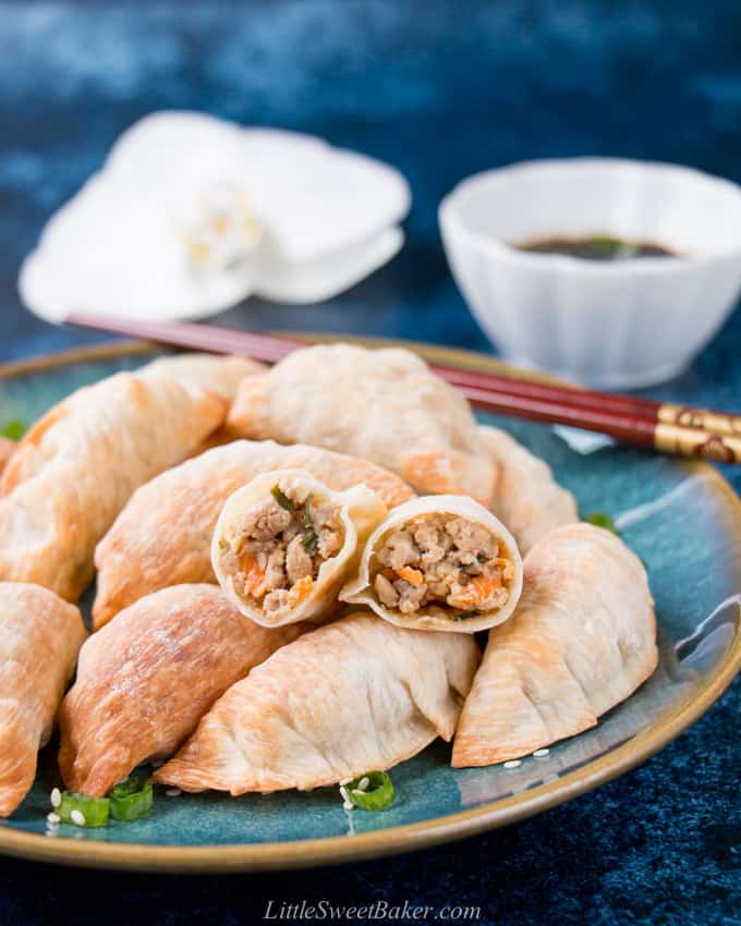 A plate of baked Chinese dumplings with one cut in half to show the filling.