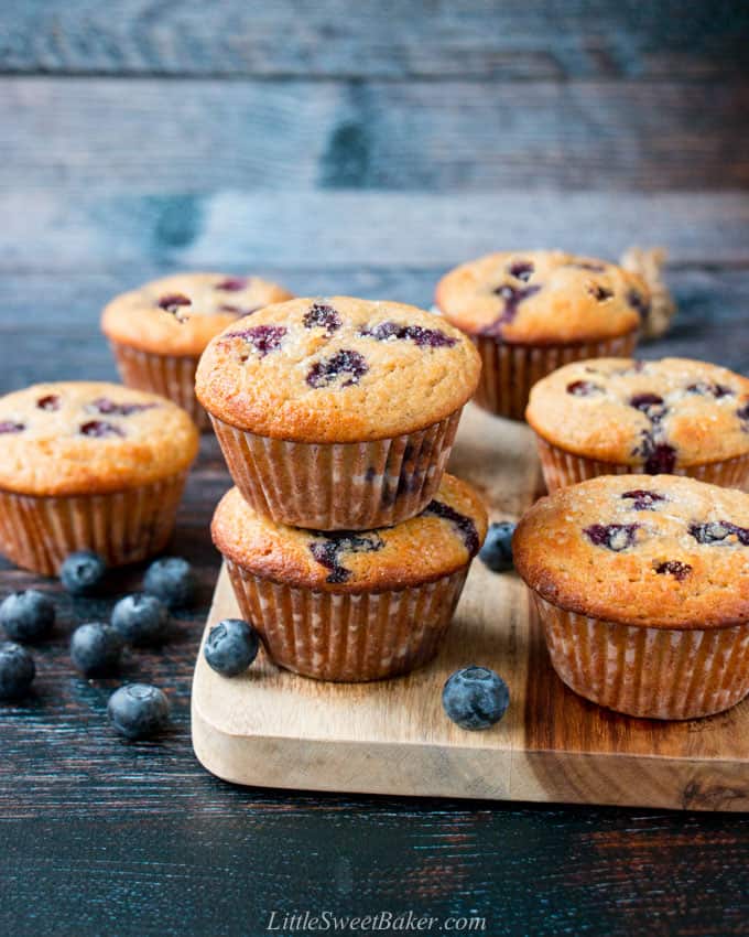 Healthy blueberry muffins on a wooden board with blueberries scattered.