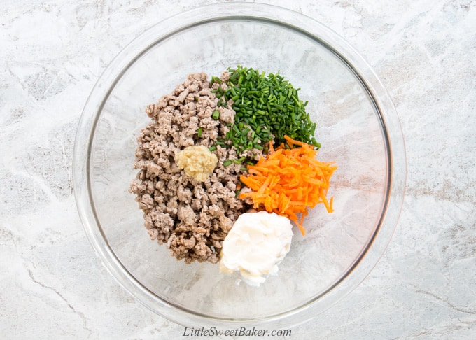 A mixing bowl of cooked ground turkey, chives, carrots, mayonnaise and ginger.