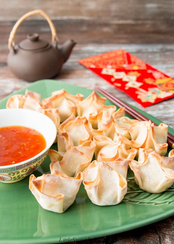 A plate of baked turkey rangoon with dipping sauce and a pair of chopstick.