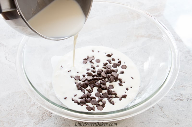 Scalded cream pouring over a bowl of semi-sweet chocolate chips.