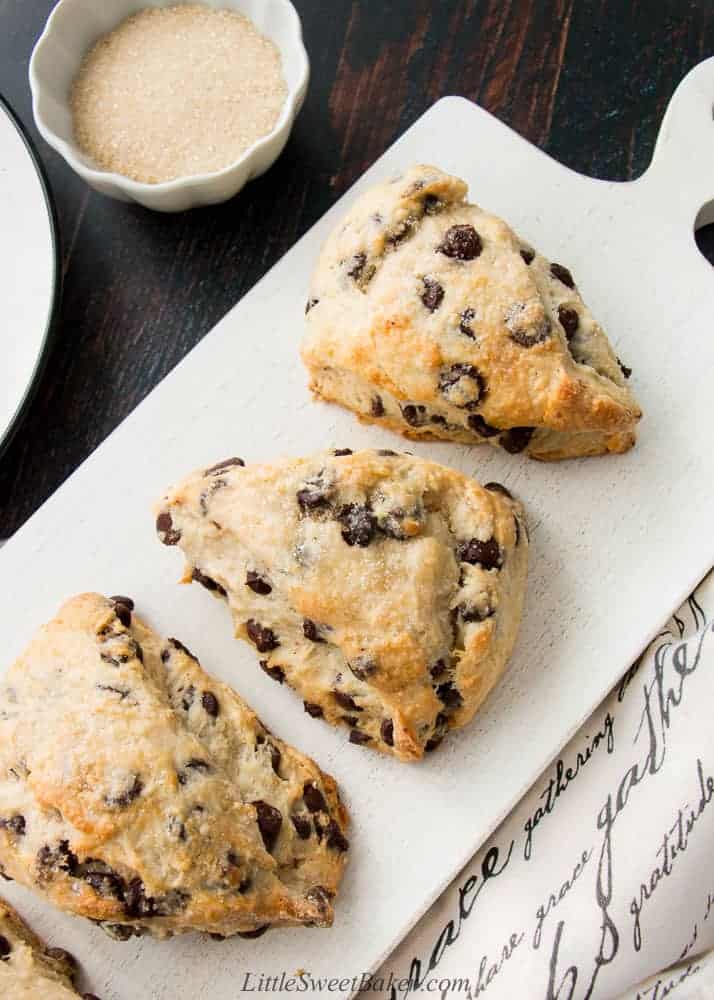 Chocolate chip scones on a white wooden board.