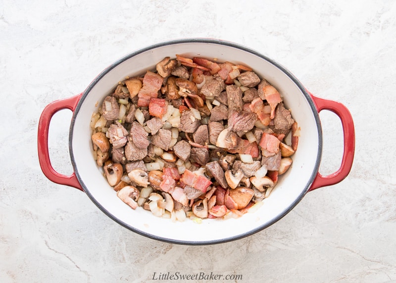 A Dutch oven filled with stew meats and veggies