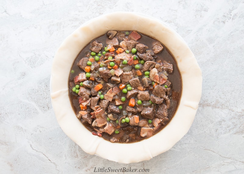 A pie plate lined with pie crust filled with beef stew