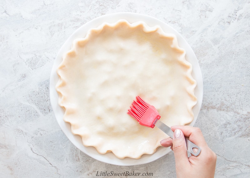 A raw pie being brushed with egg wash