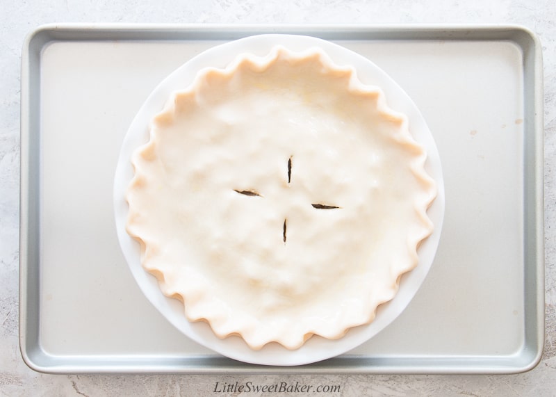 An unbaked steak and stout pie on a baking sheet