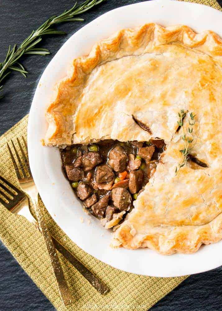 A steak and mushroom stout pie with some top crust removed to show filling.