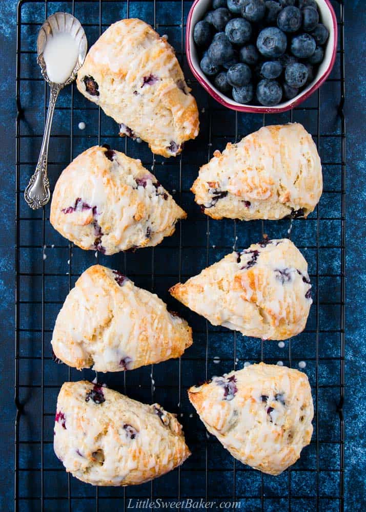 Glazed blueberry scones on a cooling rack.