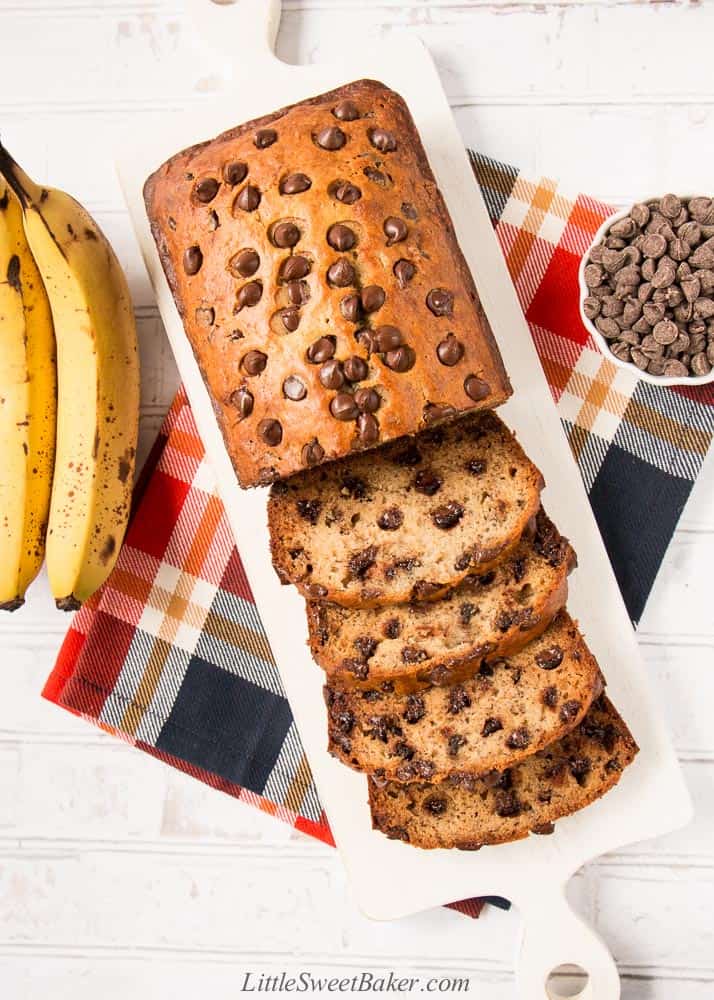 Chocolate chip banana bread on a white cutting board with a few slices cut.