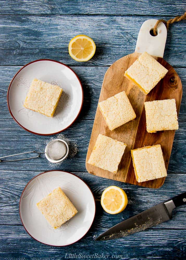 Two lemon bars in a gray and five lemon bars on a wooden cutting board.