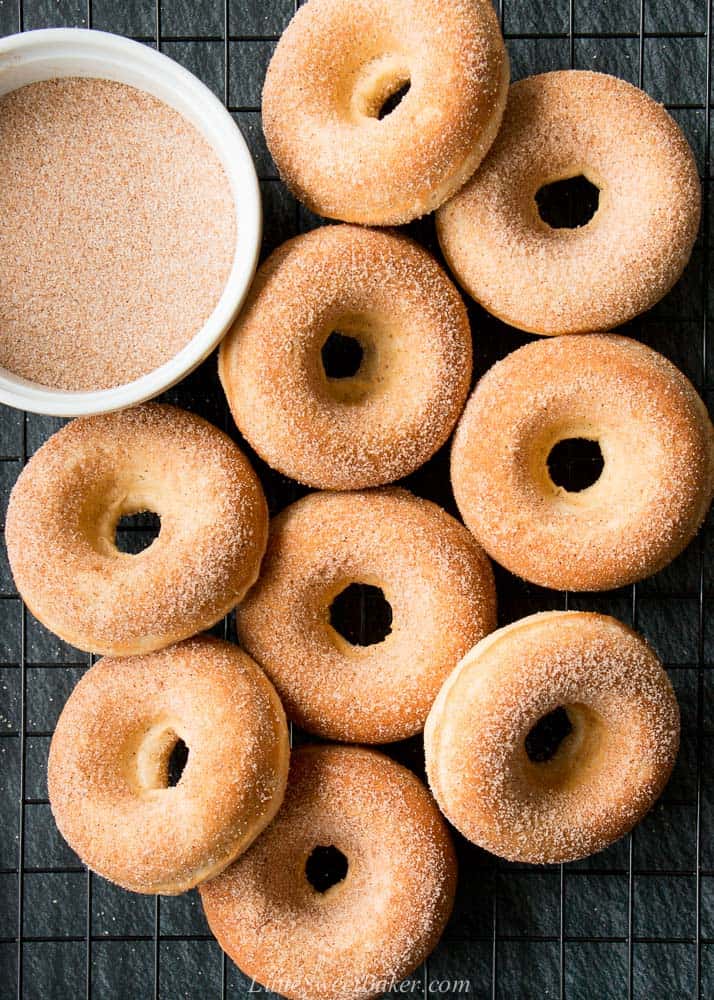 Old-fashioned donuts on a cooling rack with a bowl of cinnamon-sugar.