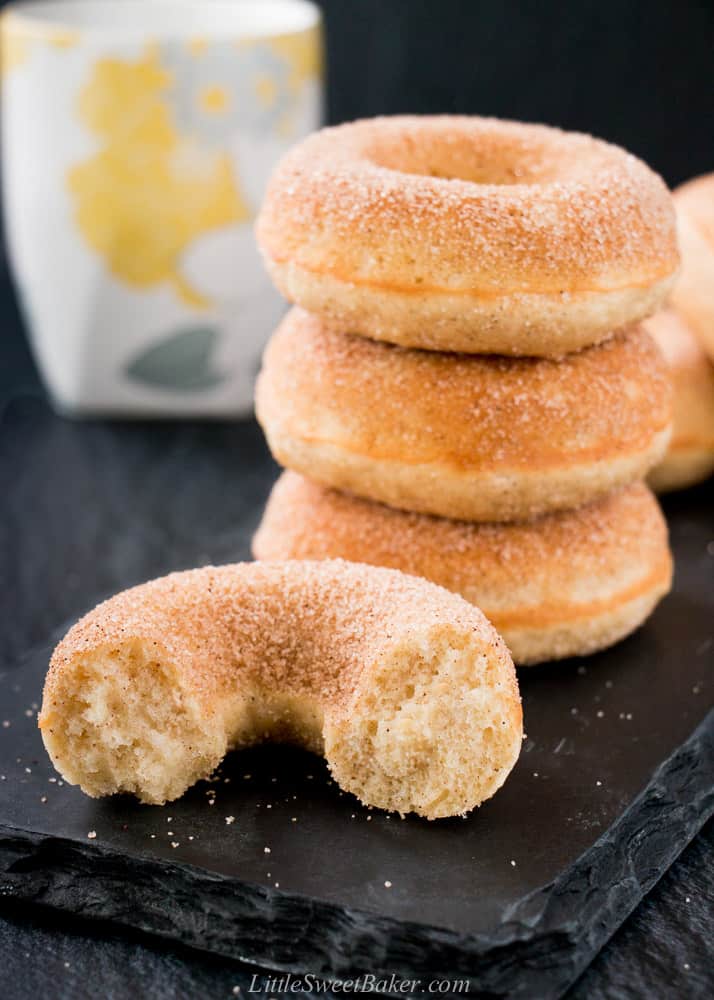 Old-fashioned donuts on a piece of black slate with one broken in half.