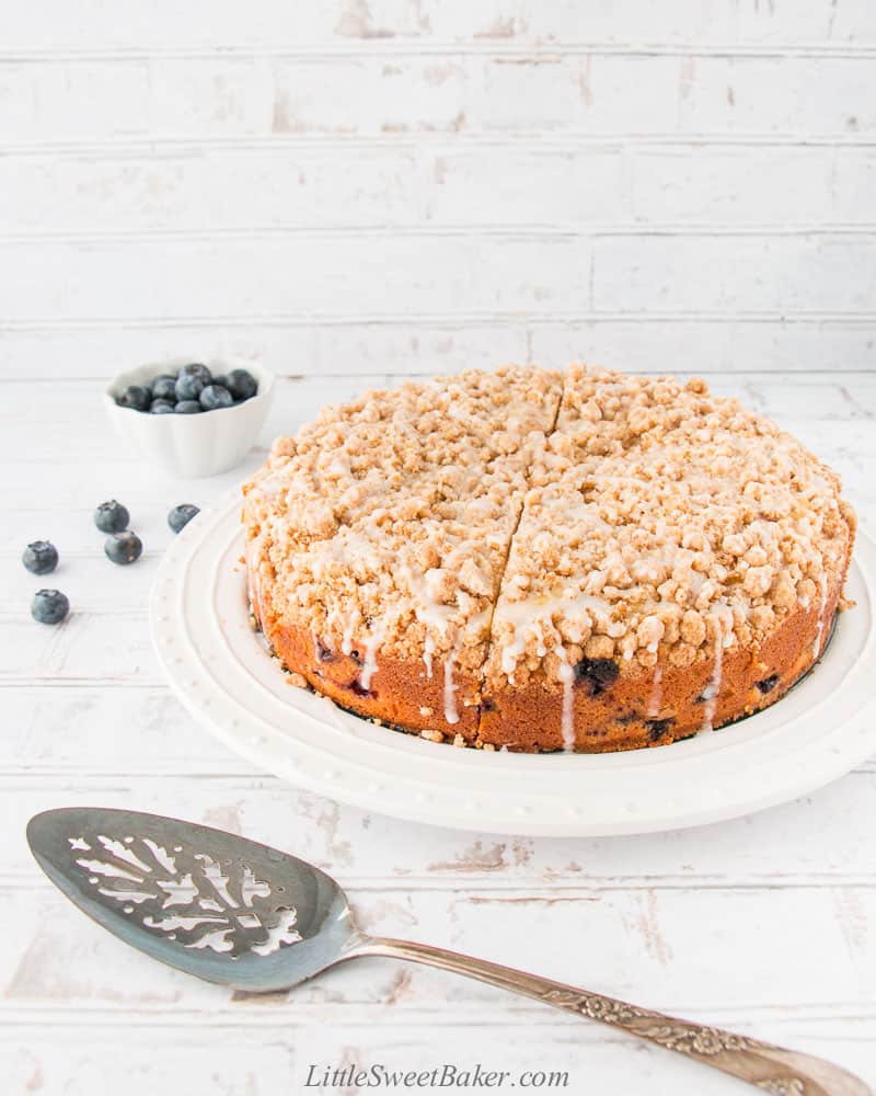 A whole blueberry crumb cake on a white plate.