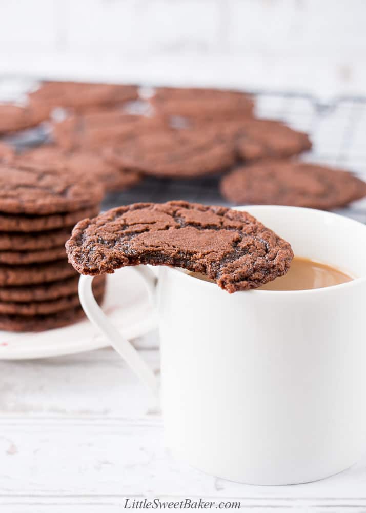 A nutella cookie with a bite taken out on a cup of coffee.