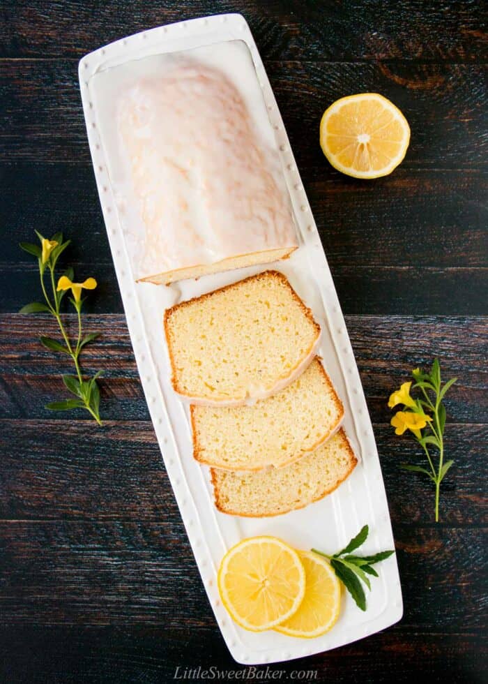 Glazed lemon pound cake with three slices cut on a white plate.