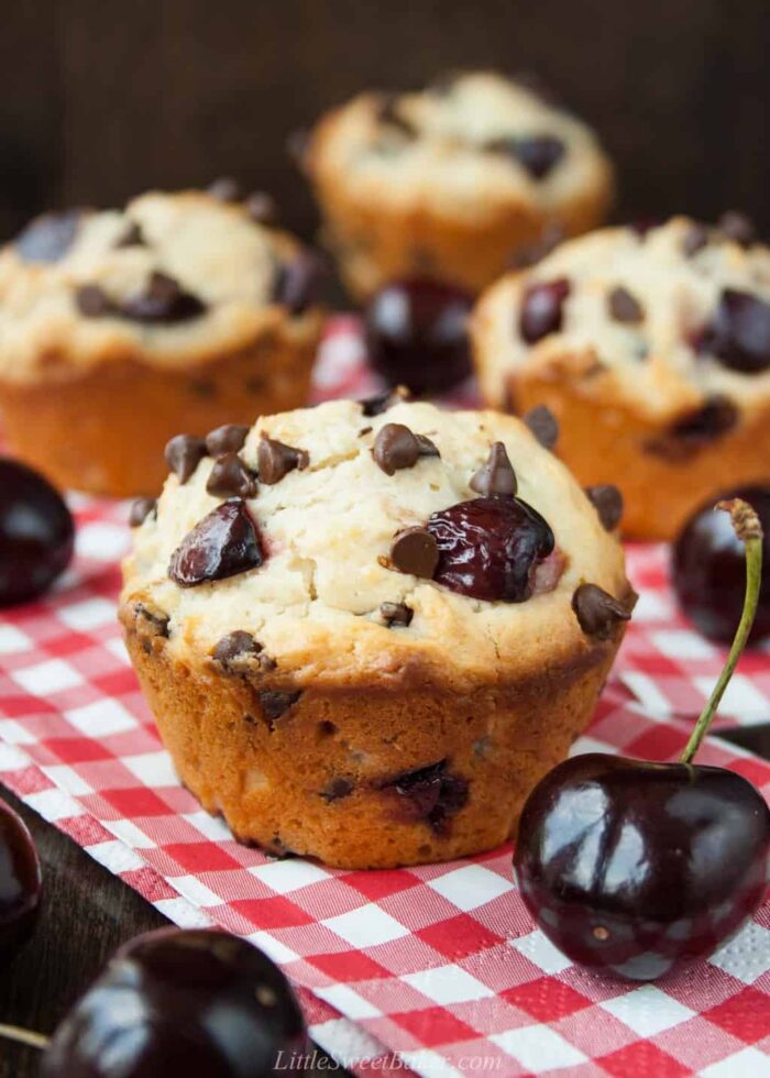 Cherry chocolate chip muffins on red plaid napkins.