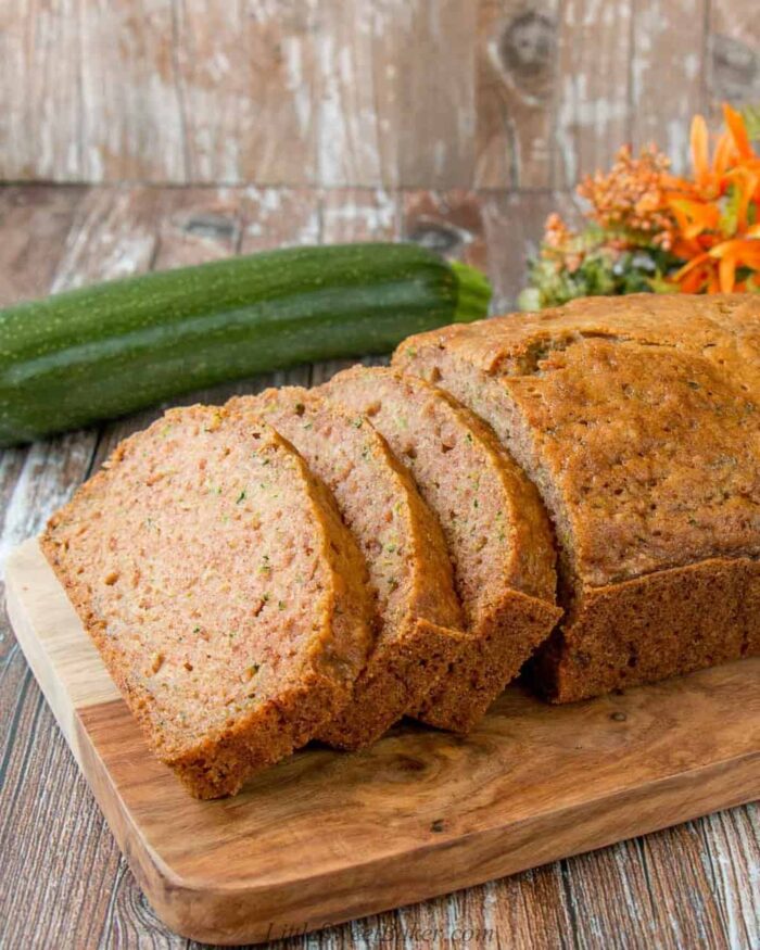 A loaf of zucchini bread on a cutting board with three slices cut.