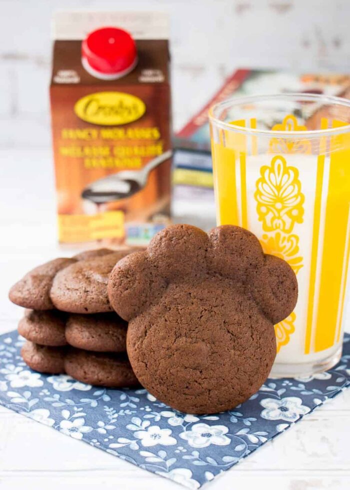 chocolate molasses bear paw cookies on a blue floral napkin with a glass of milk