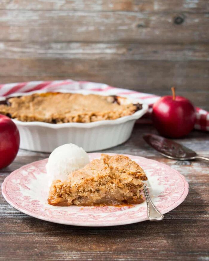 A slice of Swedish apple pie with a scoop of ice cream in a vintage plate.