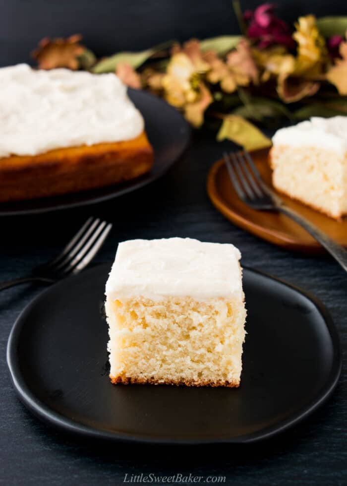 A slice of butter cake with vanilla buttercream on a black plate.