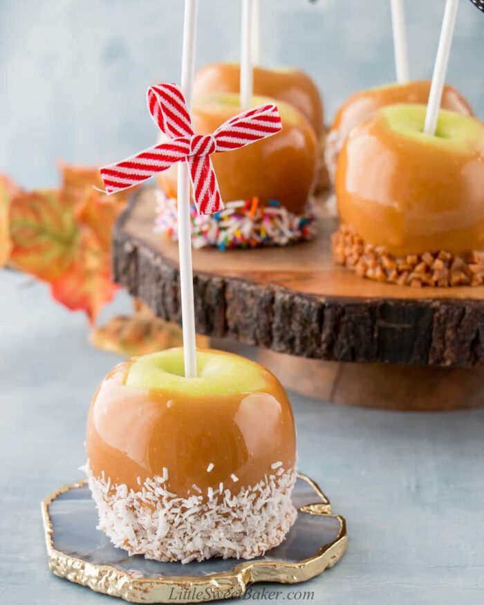 A caramel apple dipped in coconut on a quartz coaster.