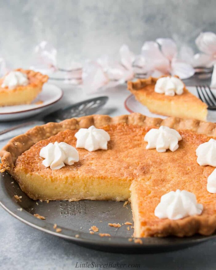 A chess pie in a metal pie pan with a quarter section missing