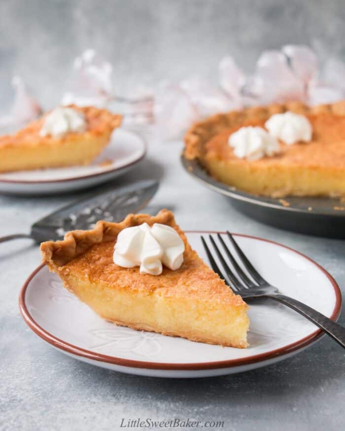 A slice of chess pie with whipped cream on a light gray plate.