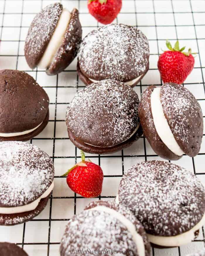 A bunch of whoopie pies on a cooling rack dusted with powdered sugar.