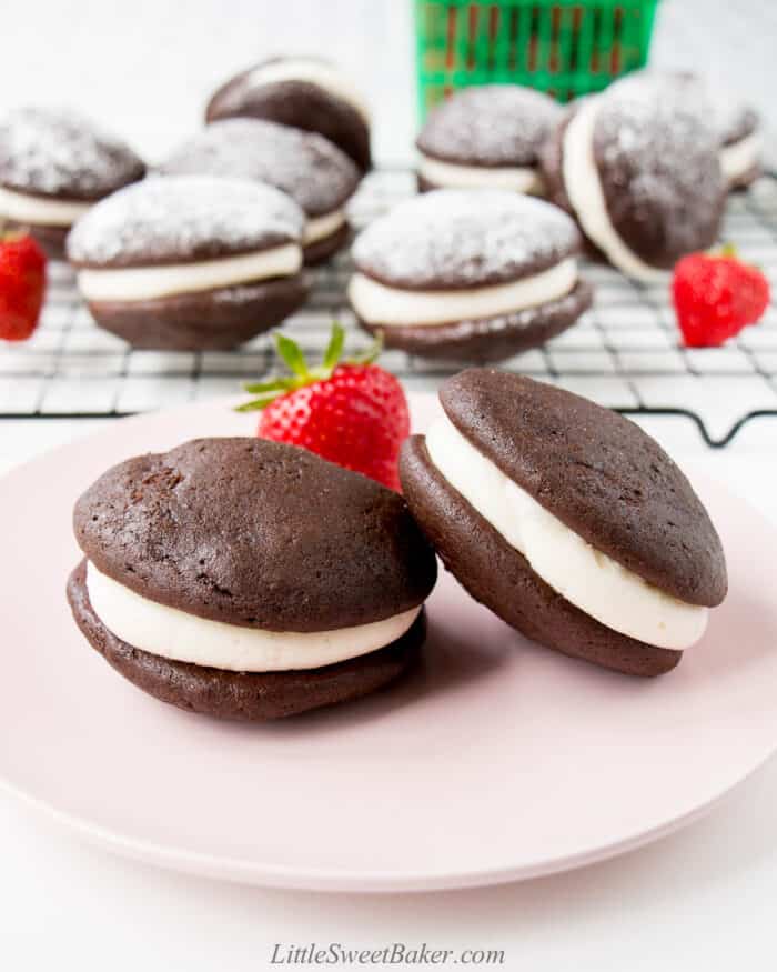 Two chocolate whoopie pies on a pink plate.