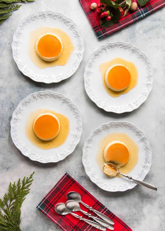 Four creme caramels on individual plates with spoons and red plaid napkins.