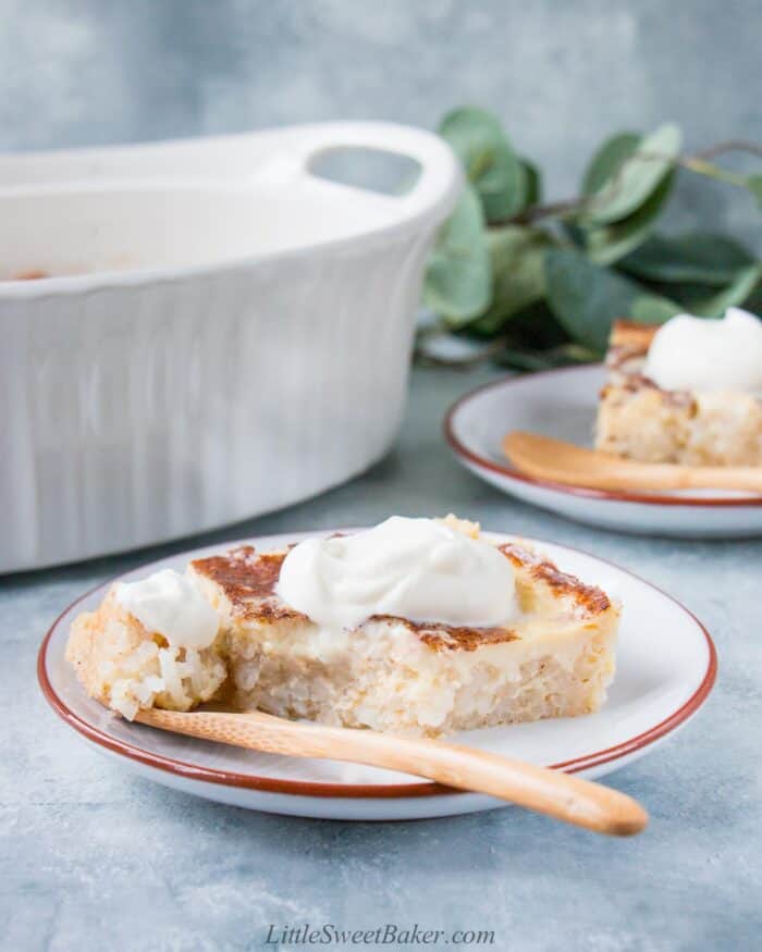 A slice of custard rice pudding with whipped cream on a plate with a wooden spoon,