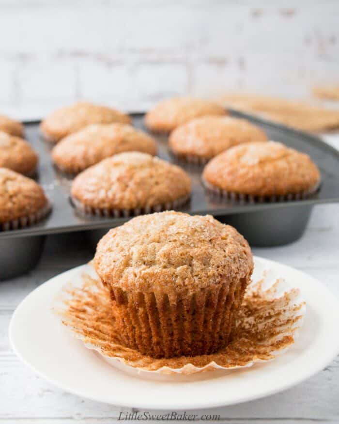 A banana muffin with its paper liner peeled on a white plate.