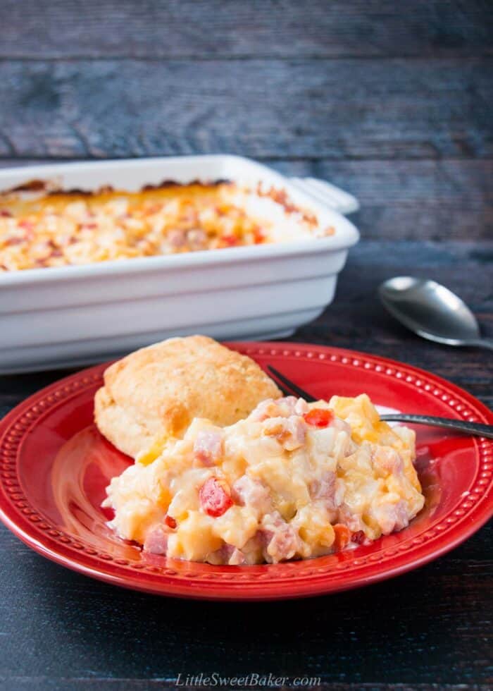 A plate of ham and potato casserole with a homemade butter biscuit.