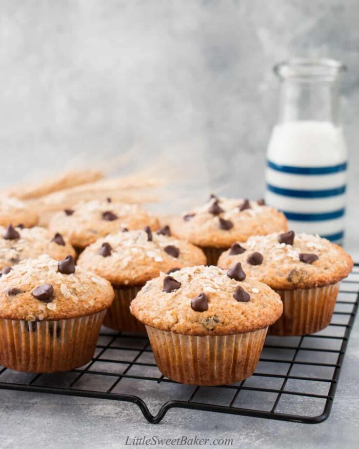 Oatmeal chocolate chip muffins on a cooling rack with a glass of milk behind.