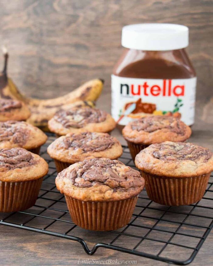 Nutella banana muffins on a cooling rack with a jar of Nutella in the background.