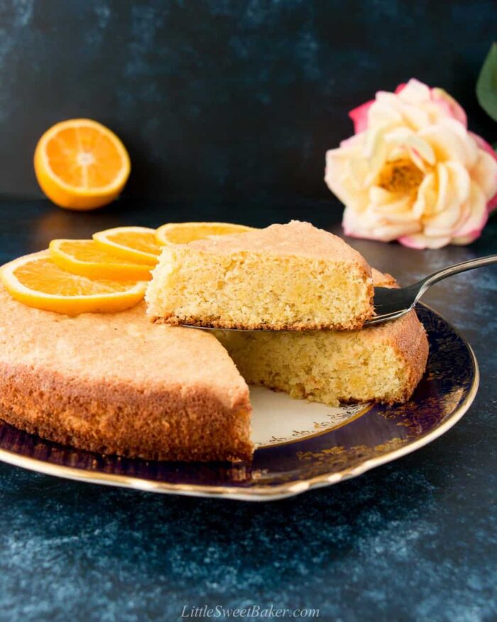 An orange almond cake on a vintage plate with a sliced lifted.