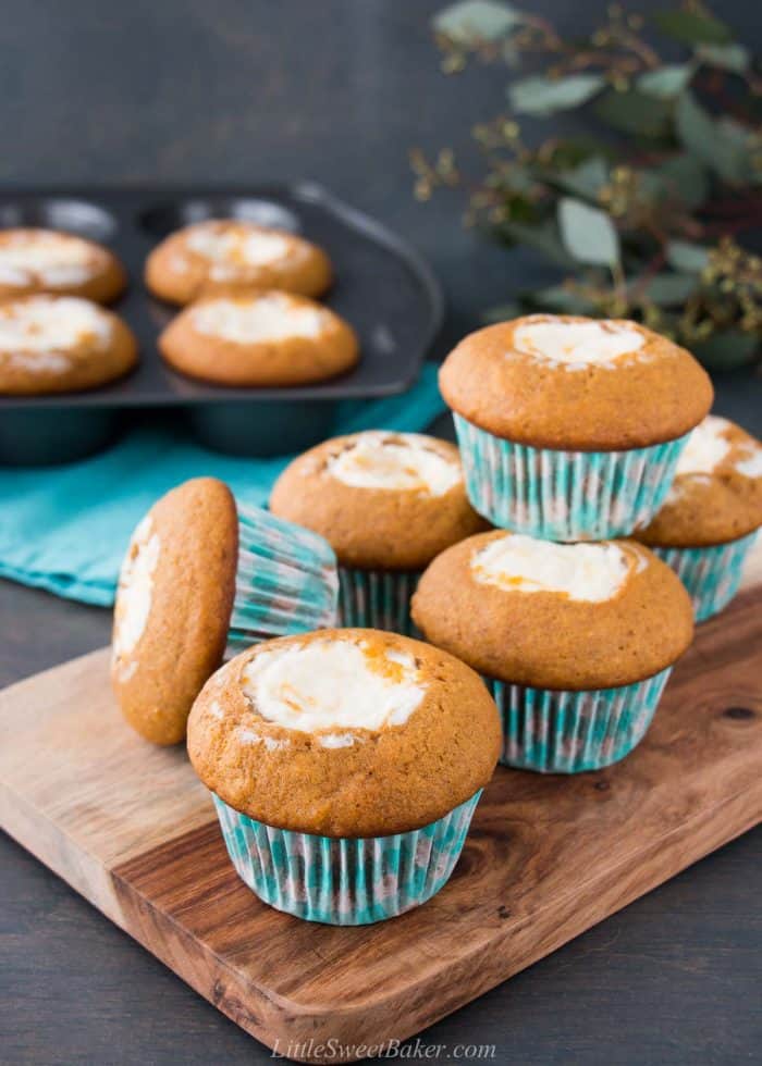 Pumpkin cream cheese muffins on a wooden cutting board.