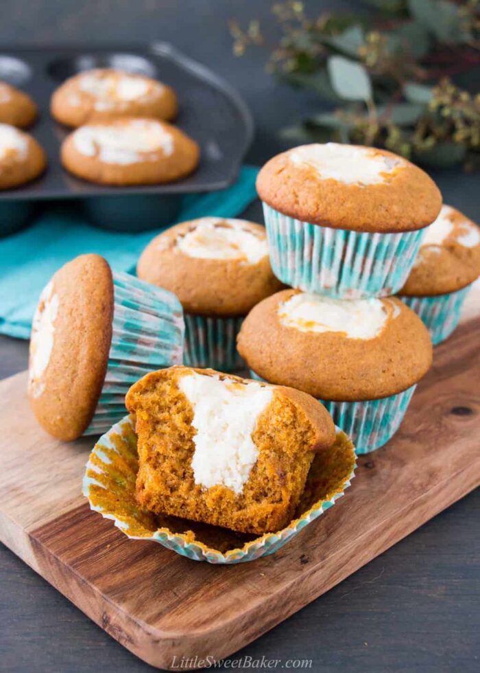 Pumpkin cream cheese muffins on a serving board with broken in half to show the inside.