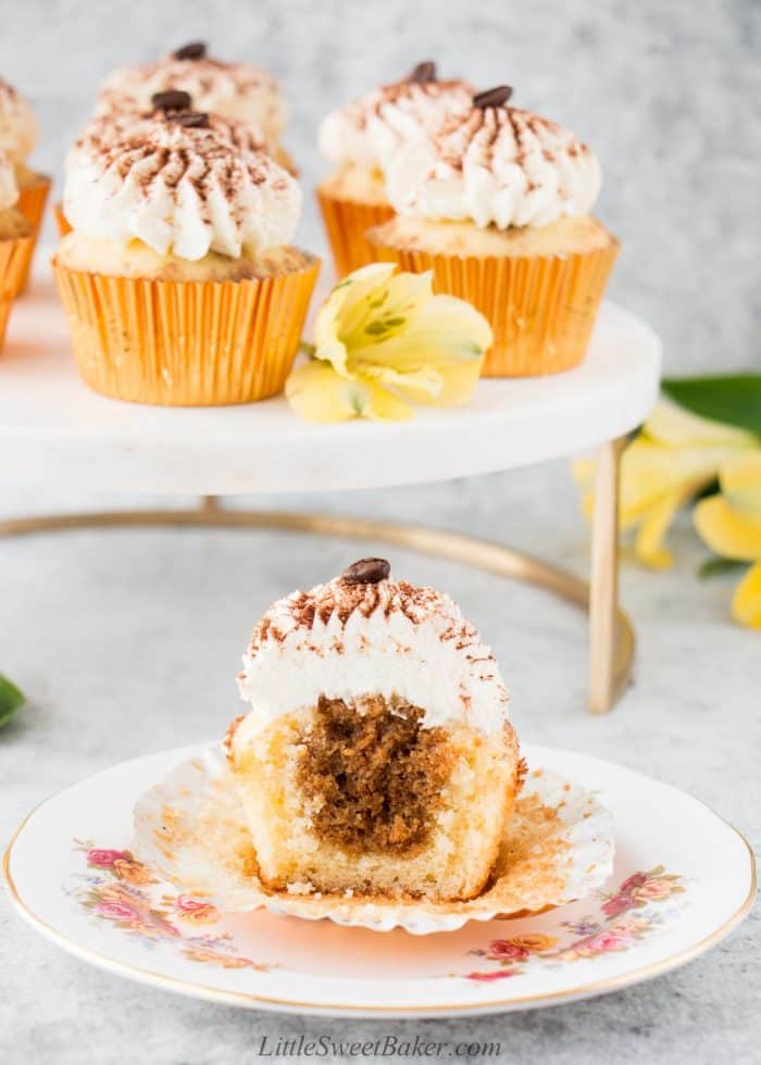 A tiramisu cupcake cut in half on a white floral plate.