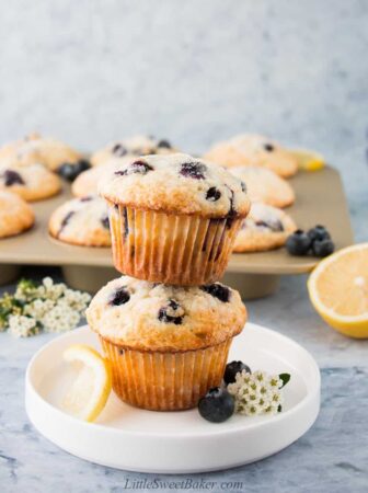 Two blueberry lemon muffins staked on a white plate.