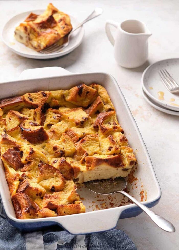 A casserole dish of easy bread pudding with a slice cut.