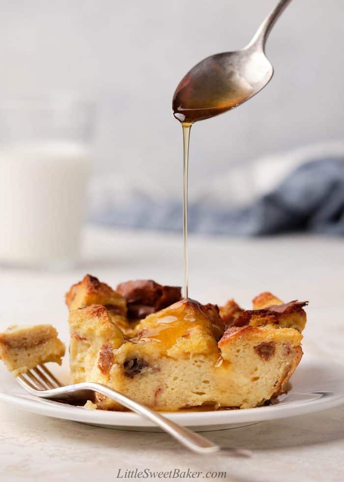 A slice of bread pudding being drizzled with maple syrup.