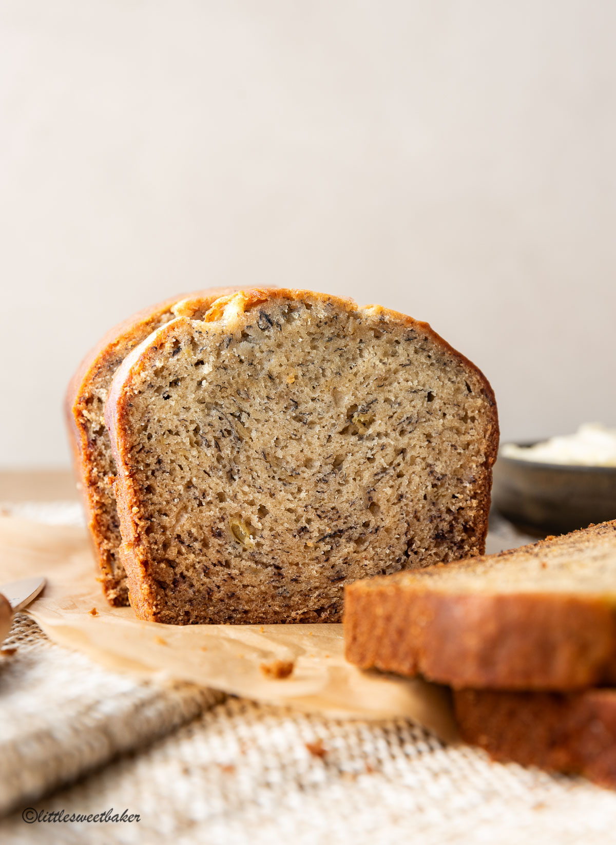 A loaf of banana bread sliced on parchment paper.