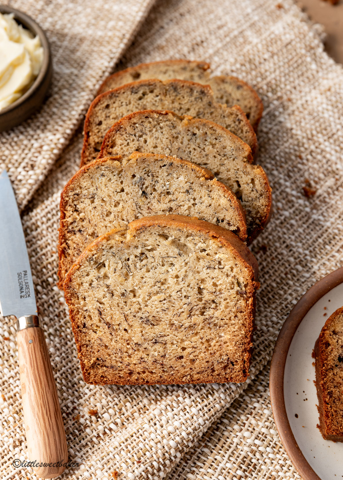 Five slices of banana bread on overlapping brown canvas napkins.