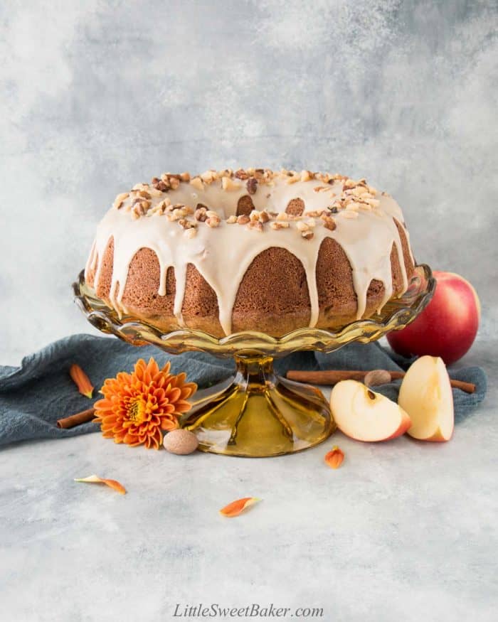 Apple bundt cake with maple glaze on a vintage cake stand.