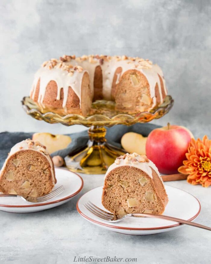 Apple bundt cake on a cake stand with two slices on plates.