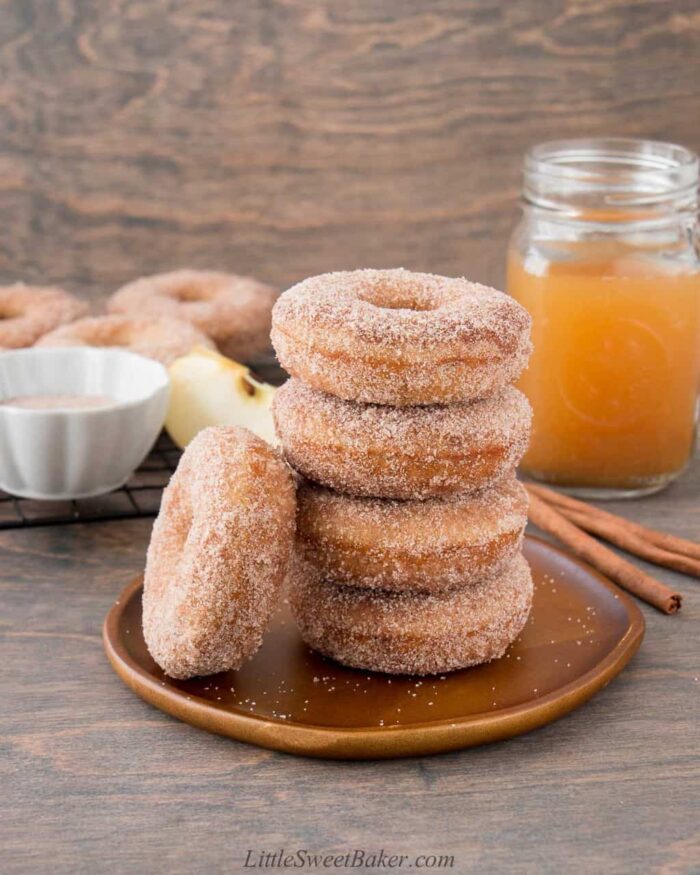 A stack of apple cider donuts on a wooden plate.