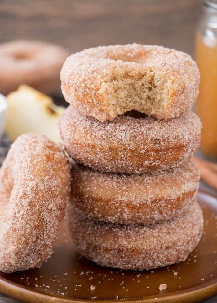 A stack of apple cider donuts with a bite taken out of the top one.