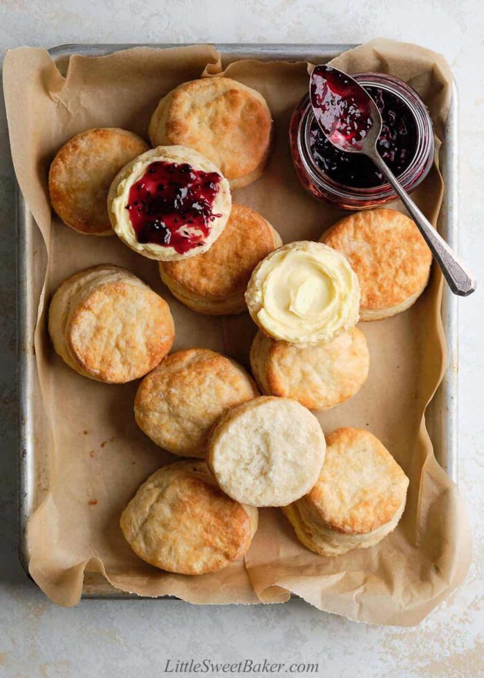 A bunch of butter biscuits scattered on a baking sheet lined with parchment paper.