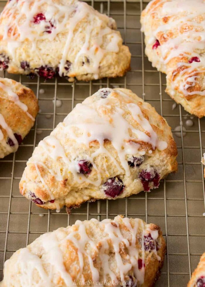 Glazed cranberry orange scones on a gold cooling rack and tray.